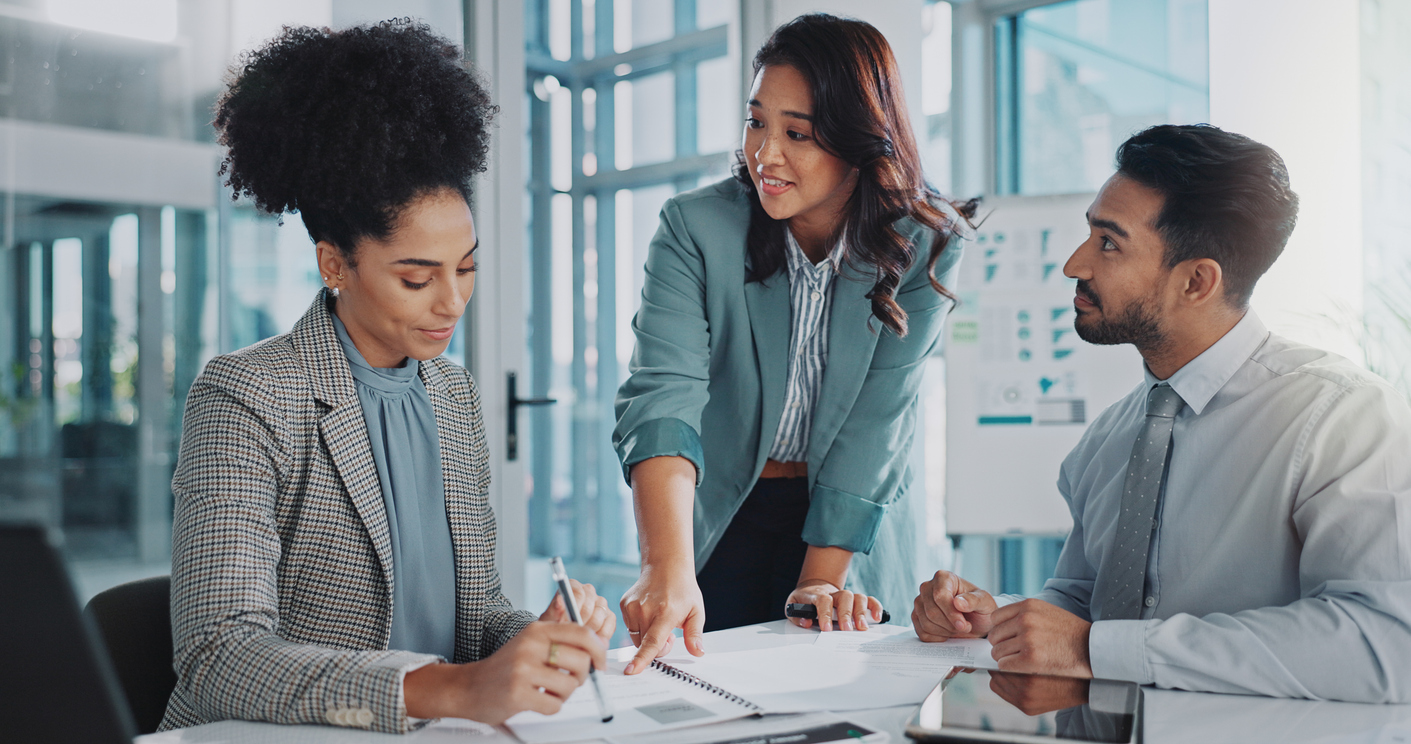 Business professionals reviewing documents during a meeting on integrating mental health support into group health insurance benefits.